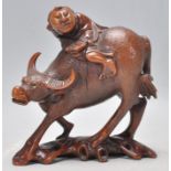 An early 20th Century Chinese carved hardwood figurine in the form of a man riding a water buffalo