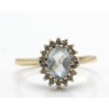 A 9ct gold and aquamarine ring. The ring with oval cut aquamarine within a halo of diamonds to