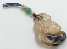 A Chinese carved figural agate pendant in the form of an animal and peach fruit
