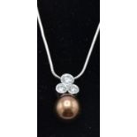 A 9ct white gold snake chain strung with a freshwater dyed brown pearl and diamond pendant.