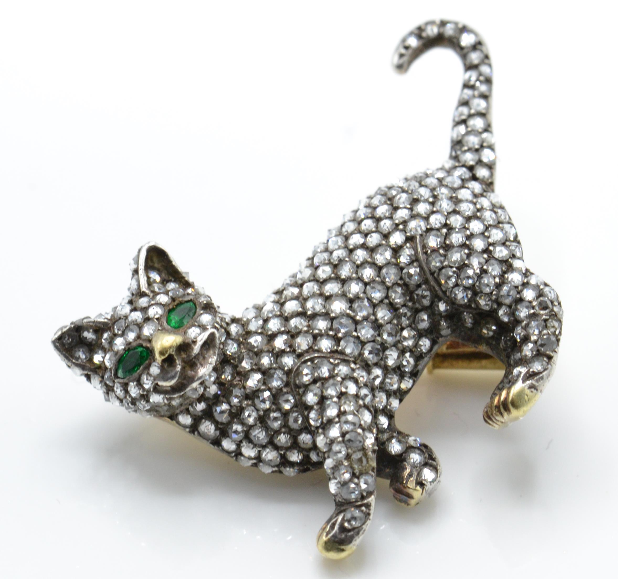 A gold emerald and diamond figural brooch pin. The brooch in the form of a cat