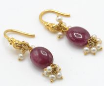 A pair of gold ruby and pearl drop earrings. The earrings strung with a large ruby beads