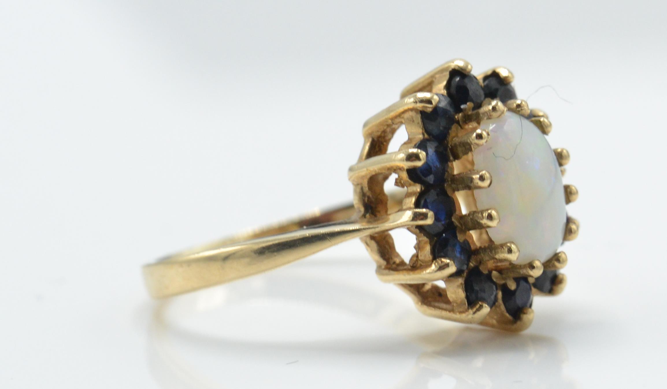A 9ct gold opal and sapphire cluster ring. The London hallmarked ring with opal cabochon - Image 3 of 4