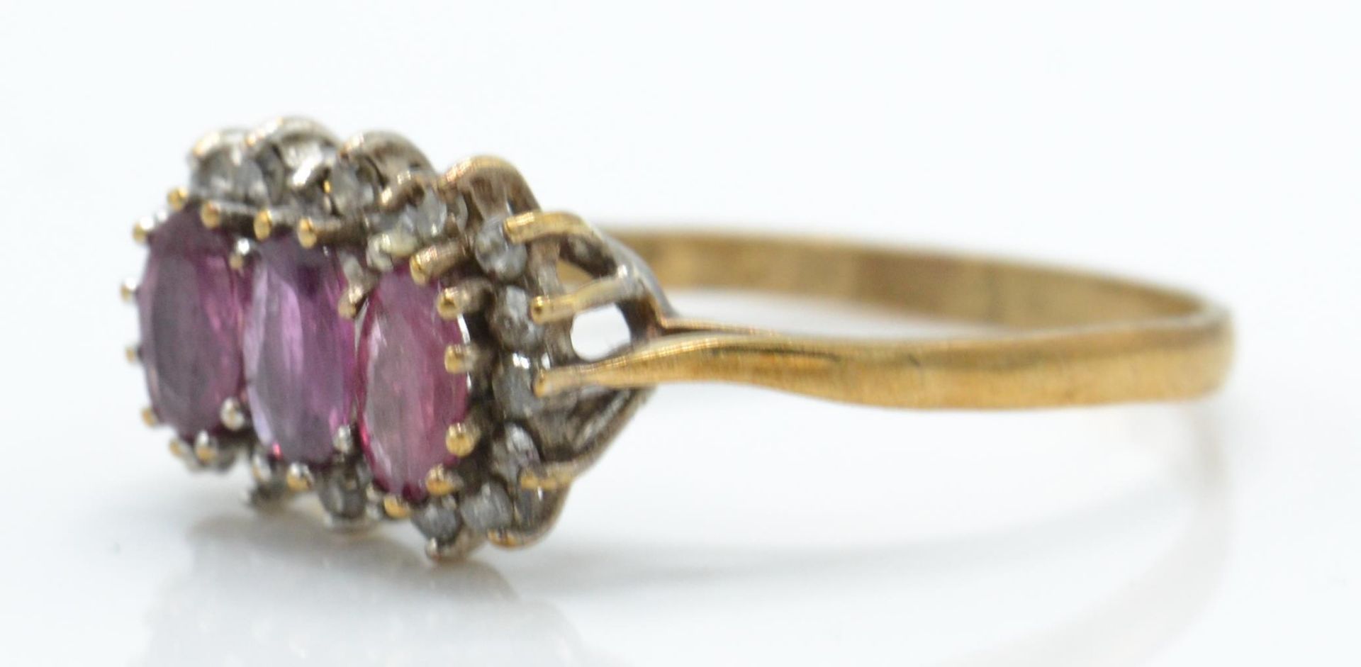 A hallmarked 9ct ruby and diamond ring. The ring set with 3 oval cut rubies surrounded by a halo of - Bild 2 aus 5