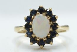 A 9ct gold opal and sapphire cluster ring. The London hallmarked ring with opal cabochon
