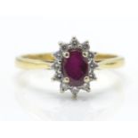 A hallmarked 18ct gold ruby and diamond cluster ring. The ring set with a central mixed cut oval