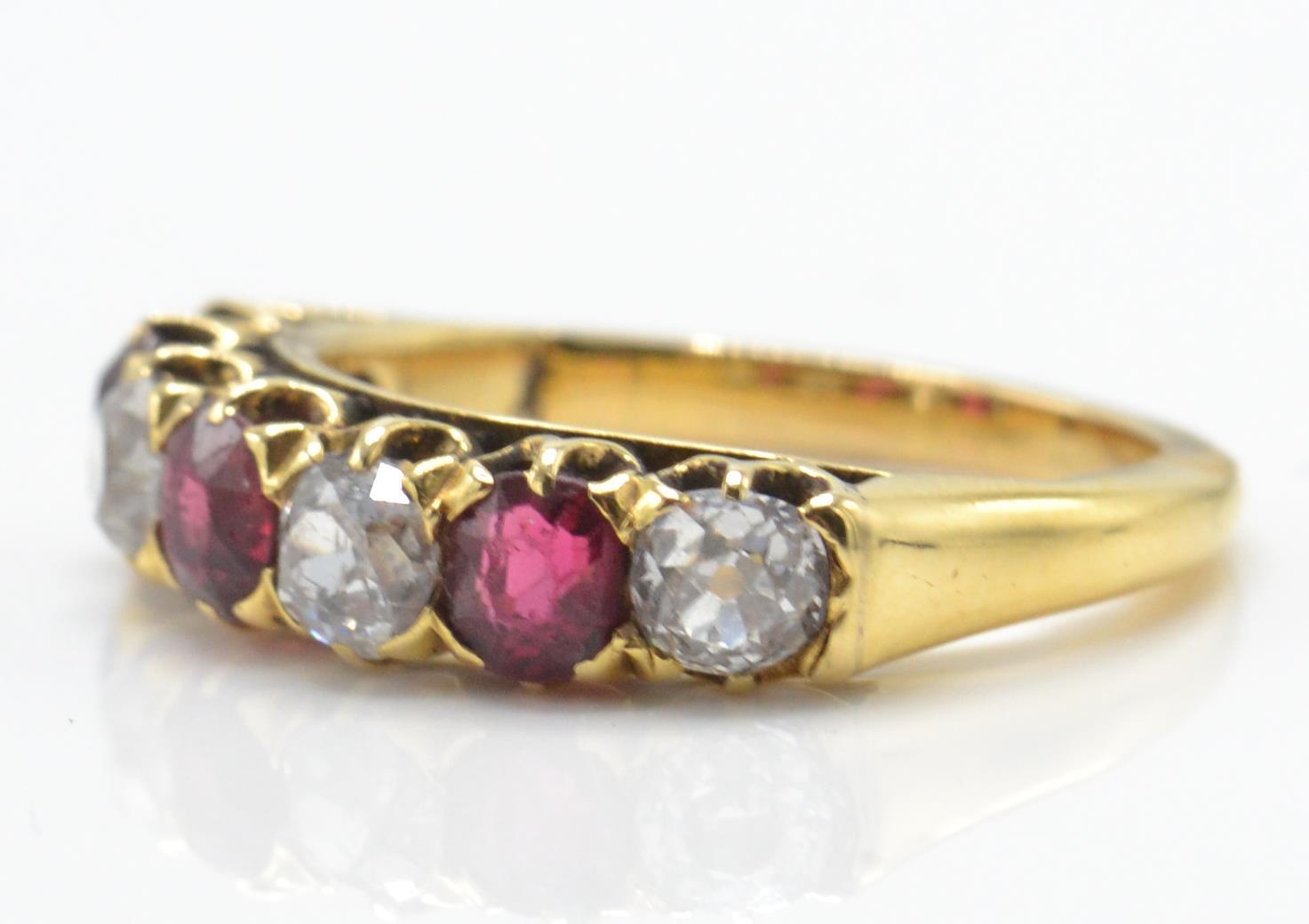 An 18ct gold garnet and diamond 7 stone band ring. The ring set with alternating garnets - Image 2 of 4