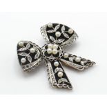A French 18ct gold and platinum Belle Epoque brooch pin. The brooch in the form of a bow