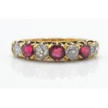 An 18ct gold garnet and diamond 7 stone band ring. The ring set with alternating garnets
