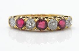 An 18ct gold garnet and diamond 7 stone band ring. The ring set with alternating garnets