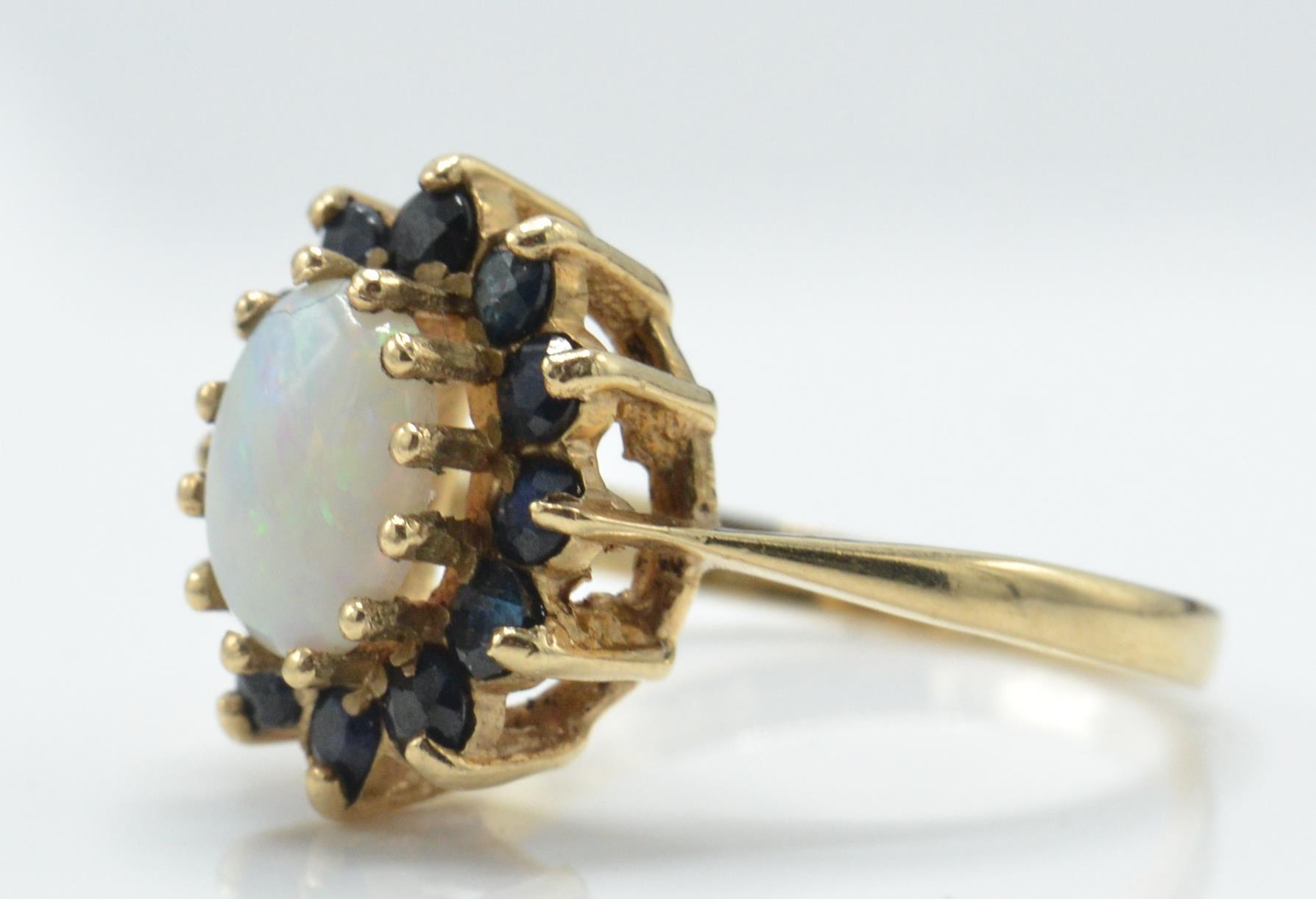 A 9ct gold opal and sapphire cluster ring. The London hallmarked ring with opal cabochon - Image 2 of 4