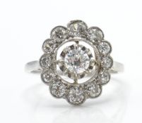 An 18ct white gold and diamond cluster ring. The ring set with a central round brilliant cut diamond