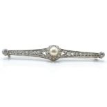 A 14ct white gold pearl and diamond bar brooch pin. The brooch set with a central pearl