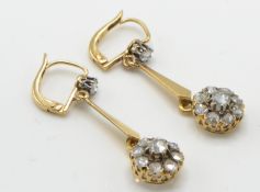 A pair of gold and diamond drop earrings. The earrings having a large rose cut diamond clusters