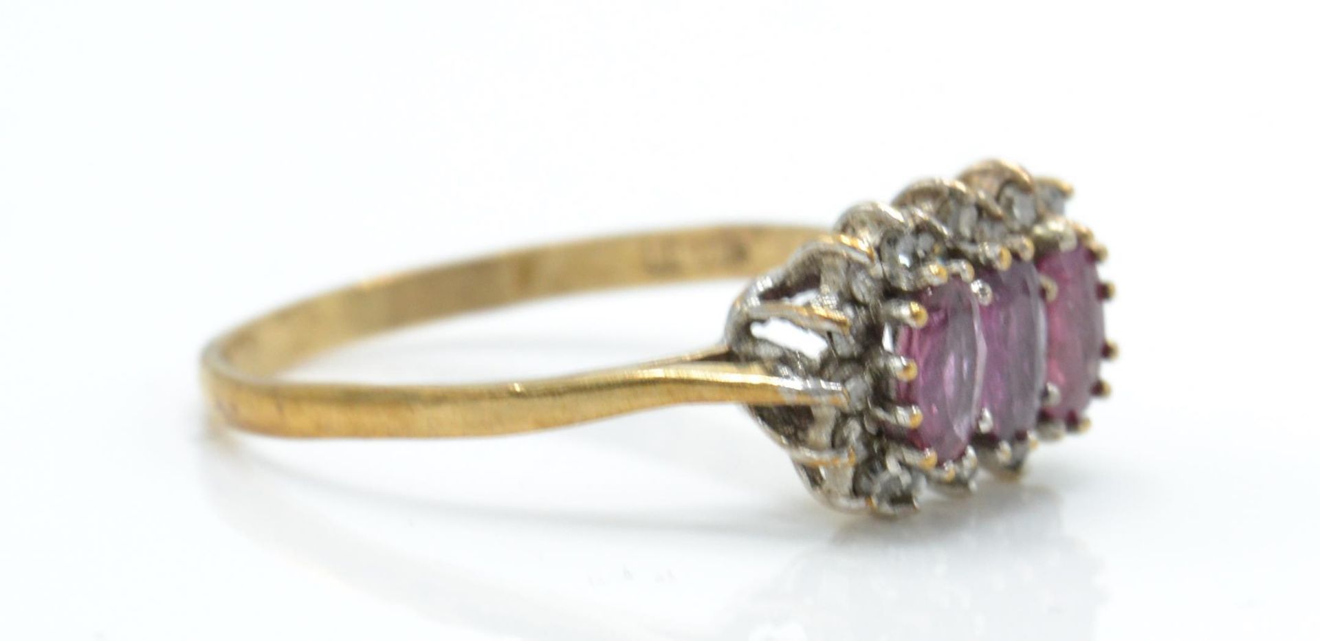 A hallmarked 9ct ruby and diamond ring. The ring set with 3 oval cut rubies surrounded by a halo of - Bild 3 aus 5