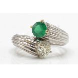 An emerald and diamond toi et moi ring. Estimated diamond weight 0.70cts
