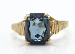 A 9ct gold and blue stone ring. The blue cushion cut sapphire within 4 prong pierced basket