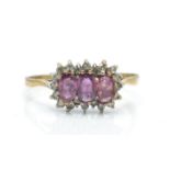 A hallmarked 9ct ruby and diamond ring. The ring set with 3 oval cut rubies surrounded by a halo of