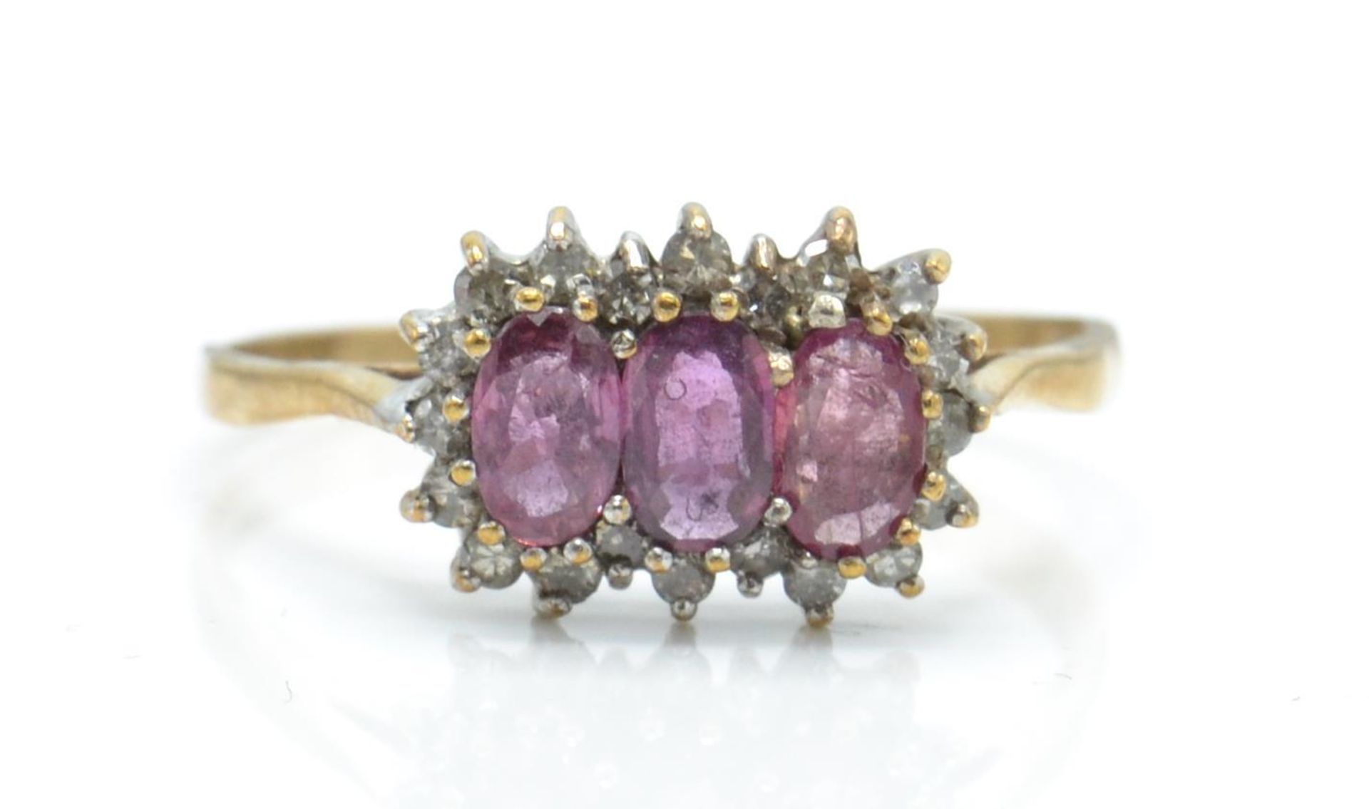 A hallmarked 9ct ruby and diamond ring. The ring set with 3 oval cut rubies surrounded by a halo of