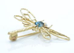 A 9ct gold and blue topaz figural brooch. The brooch in the form of a dragonfly