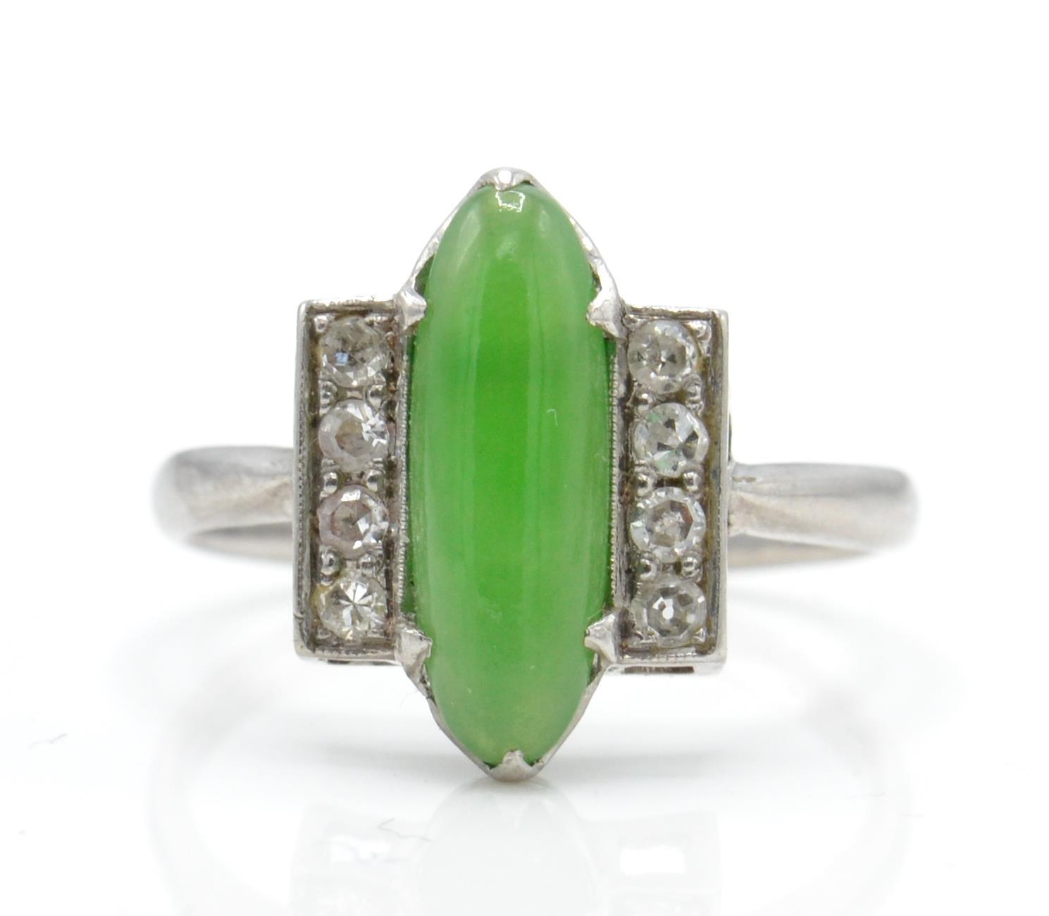 An Art Deco platinum, diamond and nephrite ring. The ring set with a green cabochon possible