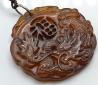 A Chinese yellow stone pendant carved into relief with scene of Qilin