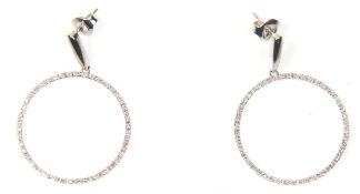 A pair of 14ct white gold drop hoop earrings being