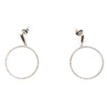 A pair of 14ct white gold drop hoop earrings being