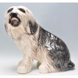 A 20th Century large glazed ceramic figure in the form of an Old English Sheepdog in a seated