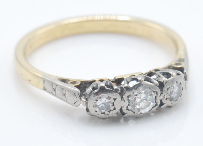 A vintage yellow gold three stone diamond ring having three round cut diamonds set into platinum