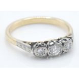 A vintage yellow gold three stone diamond ring having three round cut diamonds set into platinum