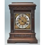 An early 20th Century 1930's antique oak cased mantel clock having a stepped plinth base with carved