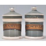 A pair of 19th Century Victorian ceramic apothecary jars having a green ground with conical lid