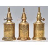 A group of three antique brass oil lamps. Two lamps marked for 'Lampe Pigeon' and the other