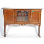 An early 20th Century Art Nouveau oak dresser top having a central glazed door with decorative red