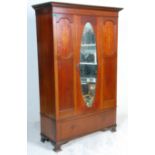 An early 20th Century Edwardian single door wardrobe having inlaid panel decoration flanking an oval