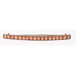 A stamped 800 silver vintage bar brooch set with eighteen coral cabochons, having a hinge pin to the