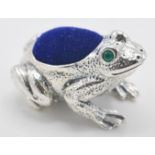 A sterling silver pin cushion in the form of a frog having a blue velvet cushion to its back and set
