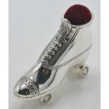 A stamped sterling silver pincushion in the form of a roller blade with a red velvet cushion to