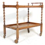 A 1920's Jacobean revival carved oak butlers tea trolley. Barley twist legs with twin tiers having