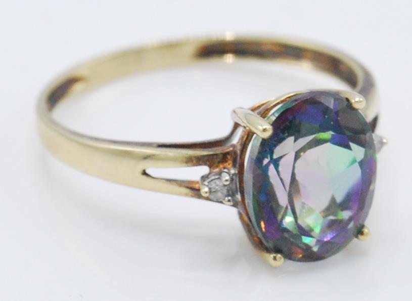 A stamped 9k yellow gold ladies dress ring set with a single faceted cut mystic topaz stone