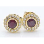 A pair of 18ct gold stud earrings being set with round cut rubies with a halo of round cut diamonds.