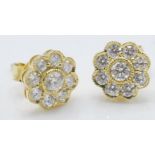 A pair of 18ct gold stud earrings having flower heads set with nine round cut diamonds in millegrain