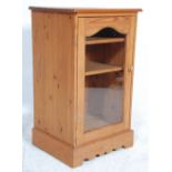 A contemporary antique style country pine cupboard unit having a flared top above a single glazed