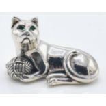 A stamped sterling silver figurine in the form of a seated cat with a ball of yarn set with green