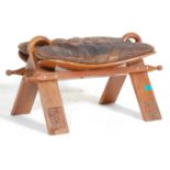 A vintage 20th Century Eastern Hardwood camel / saddle stool of typical form having a brown