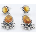 A pair of stamped 925 silver drop earrings being set with tear drop cut orange stones with marcasite