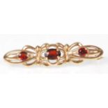 A 9ct yellow gold ladies brooch set with a central oval cut garnet flanked by two further garnets.
