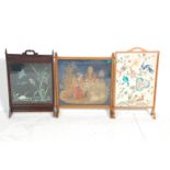 A mixed group of three oak framed fire screens with two having embroidered bird scenes with other