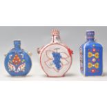 A group of three folkart / Mexican flasks made from glass with coloured leather casings.
